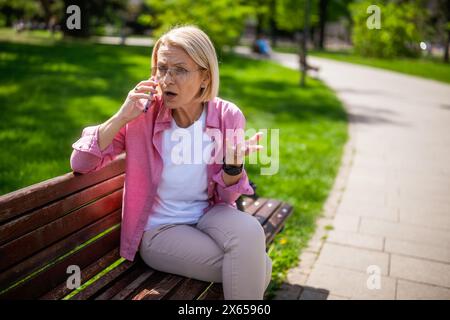 Ritratto di una donna matura nel parco. Sta parlando al telefono. Foto Stock