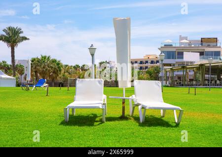 Lettini e ombrelloni sul prato verde in un resort di lusso. Perfetto per una vacanza estiva Foto Stock