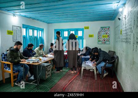 Srinagar, India. 13 maggio 2024. Le persone controllano i loro nomi sulla lista di voto all'interno di un seggio elettorale durante la quarta fase del Lok Sabha, o camera bassa, delle elezioni parlamentari indiane in un villaggio collinare a Budgam, un'area nel distretto di Budgam del collegio parlamentare di Srinagar. (Foto di Faisal Bashir/SOPA Images/Sipa USA) credito: SIPA USA/Alamy Live News Foto Stock