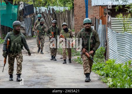 Srinagar, India. 13 maggio 2024. I soldati paramilitari indiani pattugliano la strada fuori da un seggio elettorale durante la quarta fase del Lok Sabha, o camera bassa, delle elezioni parlamentari indiane in un villaggio collinare a Budgam, un'area nel distretto di Budgam del collegio parlamentare di Srinagar. (Foto di Faisal Bashir/SOPA Images/Sipa USA) credito: SIPA USA/Alamy Live News Foto Stock