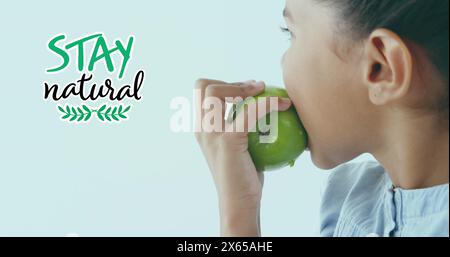 Immagine di Stay testo naturale su ragazza birazziale che mangia mela verde Foto Stock