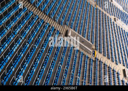 Vista ad alto angolo dei sedili vuoti blu e grigi disposti in modo ripetitivo, per catturare la tranquillità prima di un evento. Foto Stock