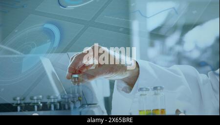 Uno scienziato che indossa un camice da laboratorio che tiene una fiala vicino alle provette di un laboratorio Foto Stock