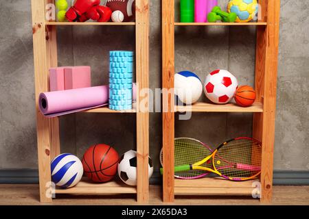 Ripiani con diverse attrezzature sportive contro il muro verde Foto Stock