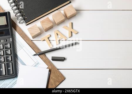 Tassa Word composta da lettere, cubi, calcolatrice, quaderno e documenti su tavolo in legno bianco, piano. Spazio per il testo Foto Stock
