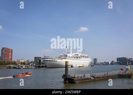 Gommone che passa per la SS Rotterdam, ex nave ammiraglia della linea Holland America, ora una barca da hotel Foto Stock