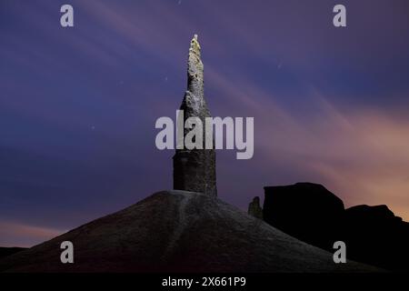 Una guglia solitaria illuminata di notte durante un luminoso sorgere di luna. Foto Stock