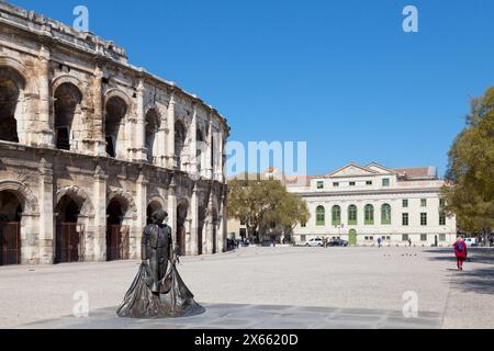 Nîmes, Francia - 21 marzo 2019: Place des Arènes (in italiano: Piazza dell'arena) con a sinistra, l'Arènes de Nîmes e il Palazzo di giustizia. Foto Stock