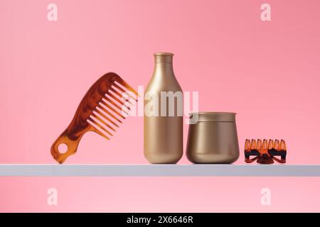 Shampoo e balsamo per capelli, vari prodotti per la cura dei capelli su ripiano nel bagno domestico, sfondo rosa. Pettine e bottiglie in plastica dorata in bagno, conf Foto Stock