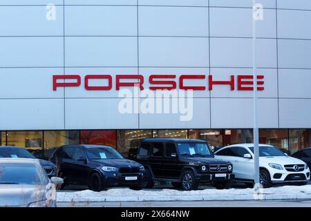 Tyumen, Russia - 18 marzo 2024: Auto parcheggiate in fila davanti a una concessionaria Porsche, con vari modelli e colori disponibili per la vendita. Foto Stock
