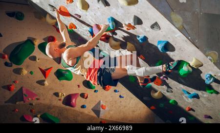 Forte scalatore esperto che pratica l'arrampicata in solitaria sul muro di Boulder in palestra. Uomo che fa esercizio presso la palestra Indoor fitness Facility, facendo sport estremi per il suo allenamento sano. Stile di vita Ritratto. Foto Stock
