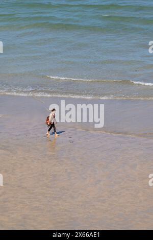 Una donna solitaria che cammina a piedi nudi attraverso la spiaggia Great Western GT Western sulla costa di Newquay in Cornovaglia nel Regno Unito. Foto Stock