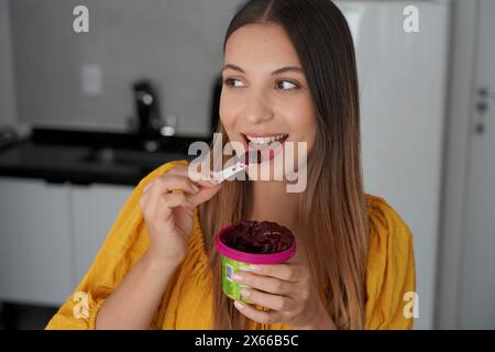 Ragazza brasiliana che mangia il gelato al sorbetto di acai dessert surgelati guardando a lato a casa Foto Stock