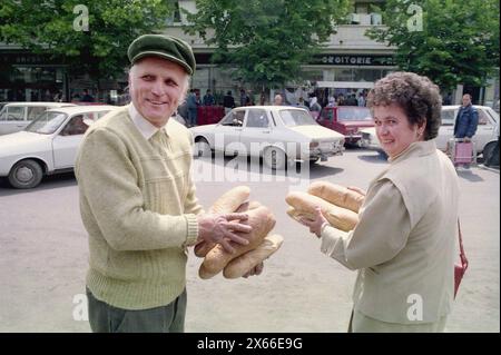 Ploiesti, Romania, maggio 1990. Pochi mesi dopo la rivoluzione anticomunista del dicembre 1989, la gente aveva ancora difficoltà a procurarsi generi alimentari di base. Il sistema economico socialista centralizzato creò scarsità e fame. Qui, un marito e una moglie stanno allegramente tenendo i pani di pane. Foto Stock