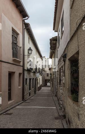 stretta strada lastricata di pietra fiancheggiata da vecchi edifici strutturati sotto un cielo nuvoloso in una città storica Foto Stock