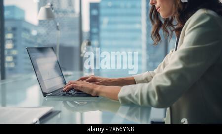 Ritratto di una giovane donna d'affari caucasica di successo seduta alla scrivania che lavora su un computer portatile nell'ufficio della città. Piano di Corporate Manager per il progetto Social Media Strategy per l'e-Commerce Foto Stock