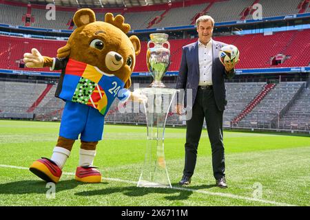 Monaco di Baviera, Germania - 13 maggio 2024: Il primo ministro Dr. Markus Söder CSU sul campo di calcio dell'Allianz Arena di Monaco. Si trova accanto alla Henri Delaunay Cup della UEFA EURO 2024 e detiene un calcio Adidas originale del Campionato europeo di calcio *** Ministerpräsident Dr. Markus Söder CSU auf dem Fußball Spielfeld der Allianz Arena di München. Er steht neben dem Henri-Delaunay-Pokal der UEFA EURO 2024 und hält einen originalen Adidas Fußball der Fußballeuropameisterschaft Foto Stock