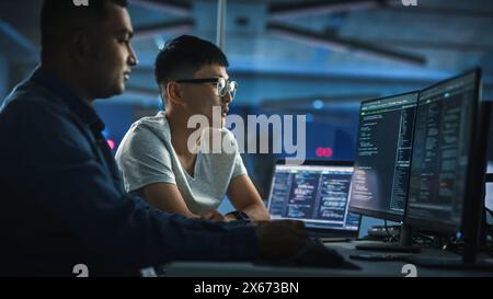 Lavoro di squadra in diversi uffici notturni: Il project manager parla con Creative Solutions Specialist e parla di computer con codice app. Professionisti alla moda programmazione, creazione di software per l'e-Commerce Foto Stock