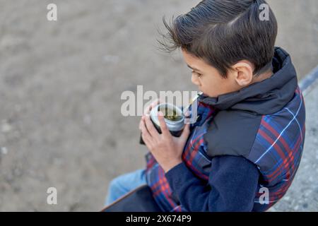 ritratto di un ragazzo latino argentino seduto fuori bevendo compagno, primo piano Foto Stock