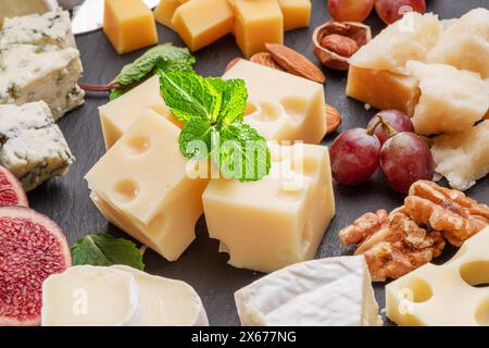 Varietà di formaggi a fette con frutta, menta, noci e taglierini. Un meraviglioso sfondo di formaggi per i vostri progetti. Foto Stock