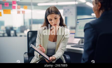 Un manager esperto e un giovane dipendente discutono di progetti commerciali, finanziari e di marketing. Young Directort che punta su tablet computer, Scolds the Employee in Modern Business Office. Foto Stock