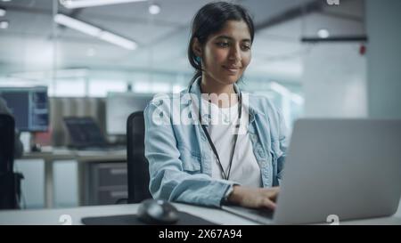 Ufficio diversificato: Ritratto di un programmatore IT indiano sorridente che lavora su un computer desktop. Specialista femminile che crea software innovativi. Un ingegnere professionista sviluppa un'app Inspirational Foto Stock