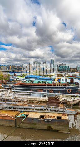 Barche da diporto e alcune fatiscenti ormeggiate sulla riva del Tamigi al Butler's Wharf a Londra, Inghilterra, Regno Unito. Foto Stock