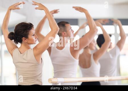 Vista posteriore di una giovane bella donna con top bianco e leggings neri che praticano posture e movimenti classici del balletto Foto Stock