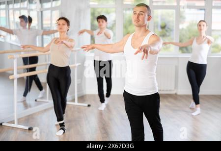 Giovane ballerino maschile esperto, vestito di bianco e nero che esegue passi di danza Foto Stock