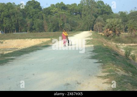 Naogaon, Bangladesh. 13 maggio 2024. Una donna torna a casa con la sua capra addomesticata attraverso il Parco Nazionale degli Altadighi di Dhamoirhat upazila nel quartiere Naogaon. (Credit Image: © MD Mehedi Hasan/ZUMA Press Wire) SOLO PER USO EDITORIALE! Non per USO commerciale! Foto Stock