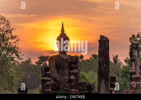 Tramonto presso una statua di Buddha del tempio Wat Mahathat, patrimonio dell'umanità dell'UNESCO, Parco storico di Sukhothai, Thailandia, Asia Foto Stock