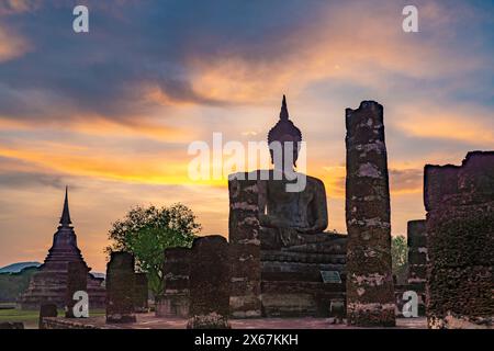 Tramonto presso una statua di Buddha del tempio Wat Mahathat, patrimonio dell'umanità dell'UNESCO, Parco storico di Sukhothai, Thailandia, Asia Foto Stock