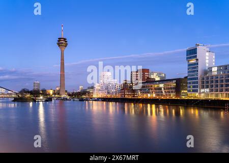 Edifici Gehry - Neuer Zollhof al Medienhafen e la torre del Reno a Düsseldorf al crepuscolo, Renania settentrionale-Vestfalia, Germania Foto Stock