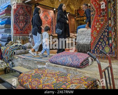 Una giovane donna iraniana con un bambino entra in un negozio di tappeti nel Vakil Bazaar. Shiraz, Iran. Foto Stock