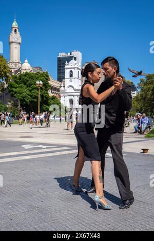 Buenos Aires, Argentina, danza di tango a Plaza de Mayo, una giovane coppia balla il tango per i turisti e i passanti locali e raccoglie un po' di soldi con un cappello, sul retro il Cabildo de Buenos Aires, un edificio ufficiale che servì come sede del governo durante il vicereame del R'o de la Plata, oggi è un museo. Foto Stock