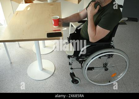 un uomo con gambe amputate in una sedia a rotelle in un bar Foto Stock