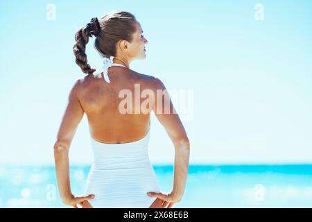 giovane donna in piedi sulla spiaggia. vista posteriore Foto Stock