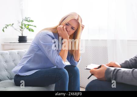 Donna che si sente in difficoltà durante la sessione di consulenza nella sala di terapia luminosa Foto Stock