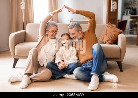 I nonni creano la forma del tetto sopra la testa delle nipoti nel soggiorno Foto Stock