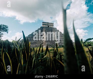 Piramide di Chichen Itza incorniciata da erba, sfondo cielo vivace Foto Stock
