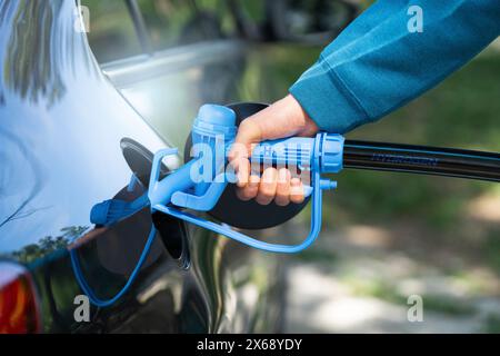 L'uomo ha un ugello di alimentazione dell'idrogeno. Rifornimento di carburante per auto con idrogeno. Concetto... Foto Stock