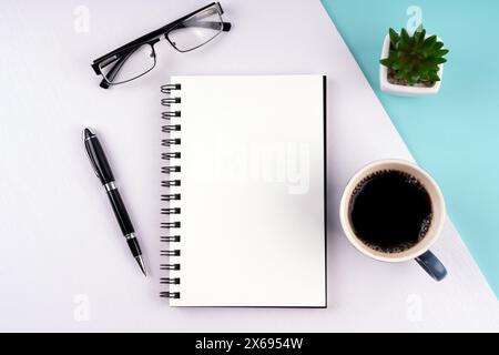 Blocco note vuoto, caffè, penna, occhiali e piante succulente Foto Stock