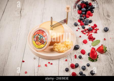 23 febbraio 2023 Lione, Francia: FAMOSO formaggio svizzero Tete de Moine con frutti rossi su un tavolo di legno bianco Foto Stock