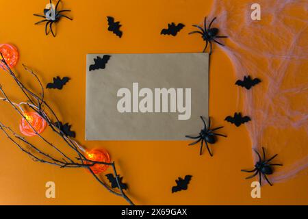 Decorazioni di Halloween, zucche, pipistrelli, ragnatela, insetti su sfondo arancione. Biglietto d'auguri per la festa di Halloween con spazio per fotocopie. Disposizione piatta, vista dall'alto. Foto Stock