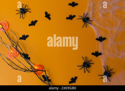 Decorazioni di Halloween, zucche, pipistrelli, ragnatela, insetti su sfondo arancione. Biglietto d'auguri per la festa di Halloween con spazio per fotocopie. Disposizione piatta, vista dall'alto. Foto Stock