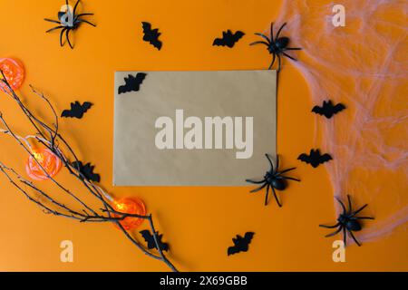 Decorazioni di Halloween, zucche, pipistrelli, ragnatela, insetti su sfondo arancione. Biglietto di auguri con spazio per il testo. Posizione piatta. Foto Stock