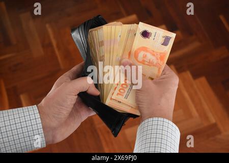 uomo d'affari che prende molte banconote da 1000 dollari argentini dal portafoglio Foto Stock