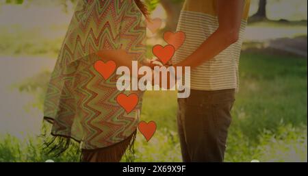 Immagine delle icone del cuore sopra la coppia caucasica che si tiene per mano Foto Stock