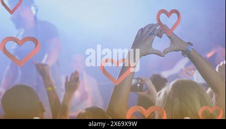 Immagine di icone del cuore su persone diverse durante il concerto Foto Stock