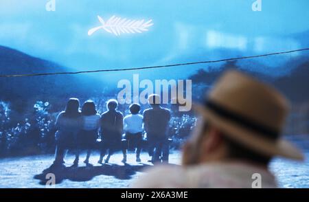 Cannes, Francia. 13 maggio 2024. Un uomo passa davanti a un enorme poster della 77a edizione del Festival di Cannes fuori dal Palais du Festival di Cannes, Francia meridionale, 13 maggio 2024. Il festival di quest'anno si svolge dal 14 al 25 maggio. Crediti: Gao Jing/Xinhua/Alamy Live News Foto Stock